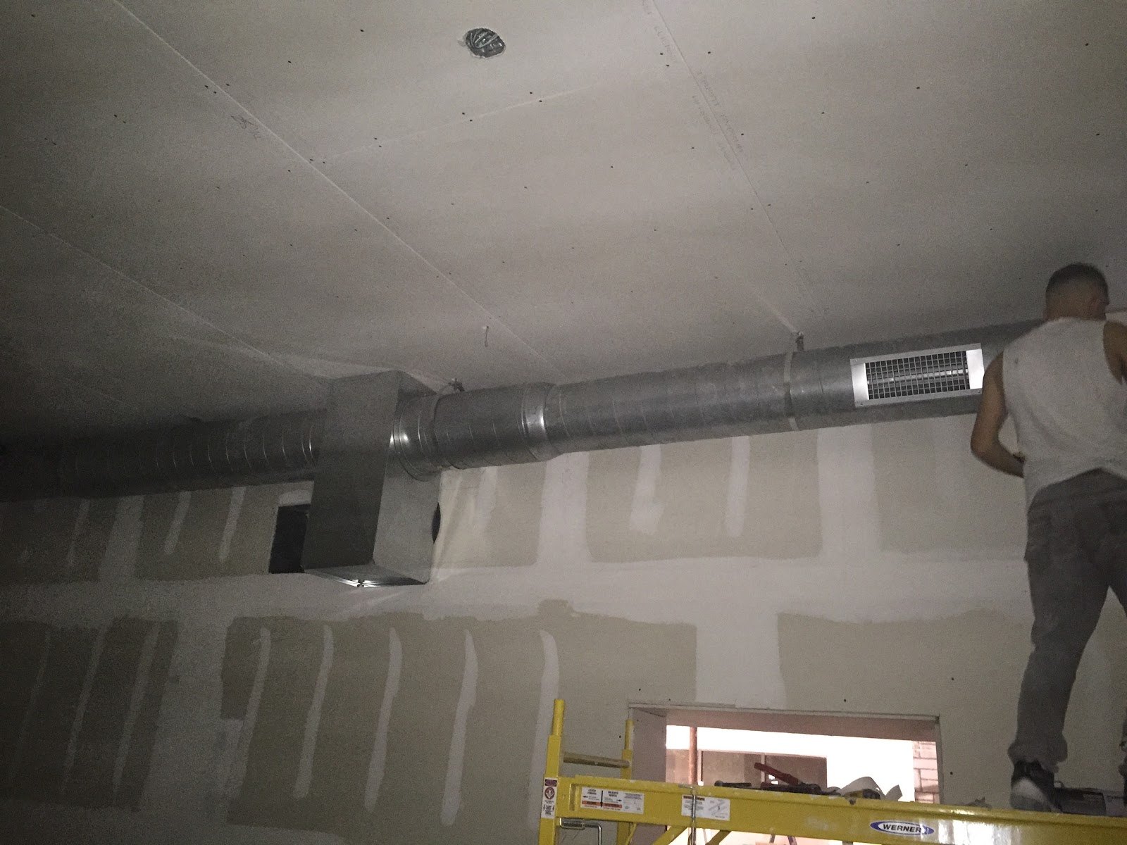 Round supply duct and register being installed above a finished ceiling by Sam's HVAC